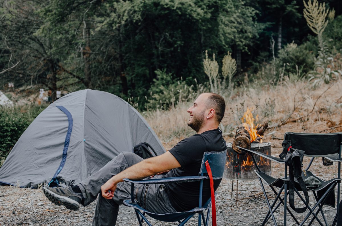 Ömer sitting by a tent and campfire