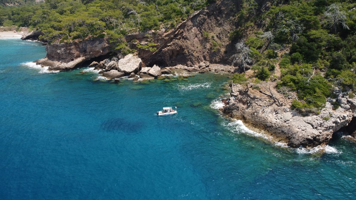 Drone view of a lone boat anchored in a turquoise cove