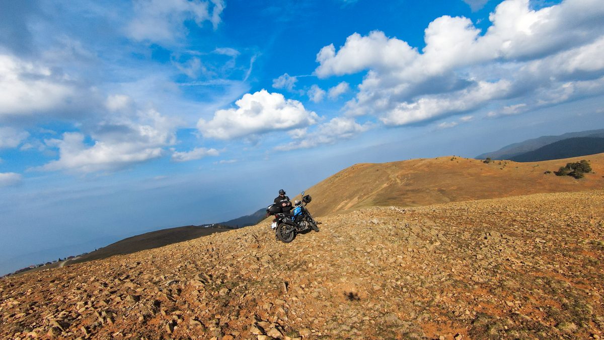 Motorcycle on a bare ridge under a big blue sky, seen from a drone