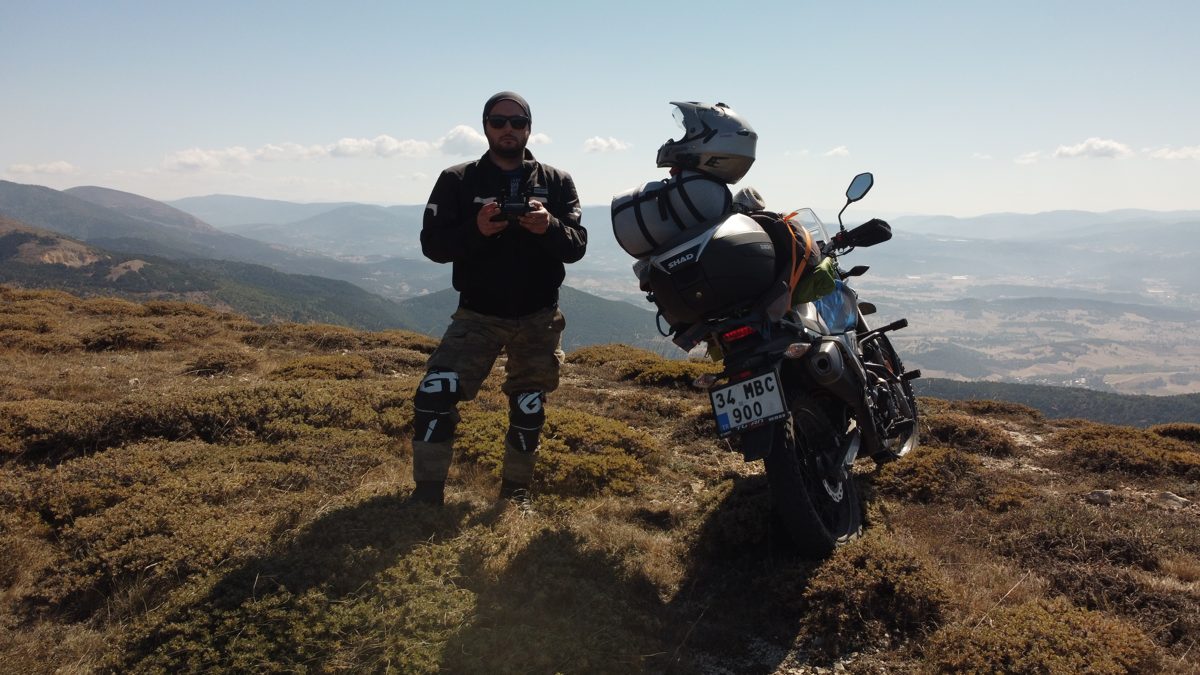 Ömer beside his motorcycle on a high plateau