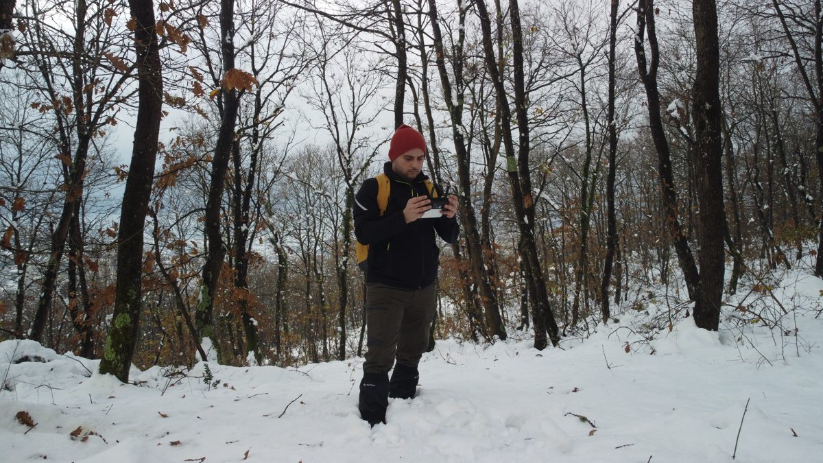 Hiker in a red beanie walking through a snowy forest